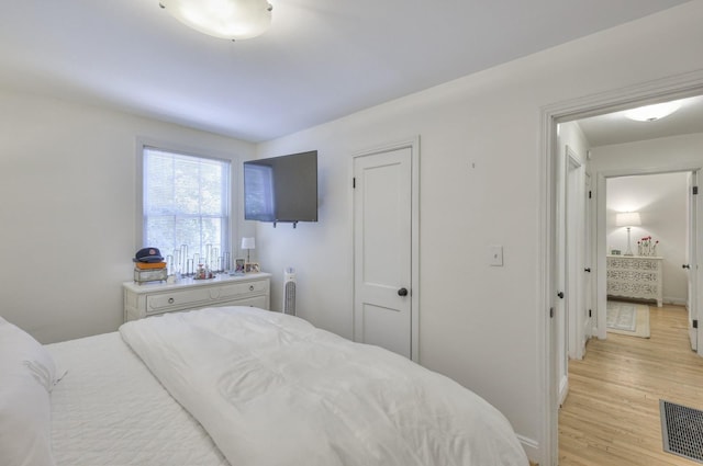 bedroom with visible vents, light wood-style flooring, and baseboards