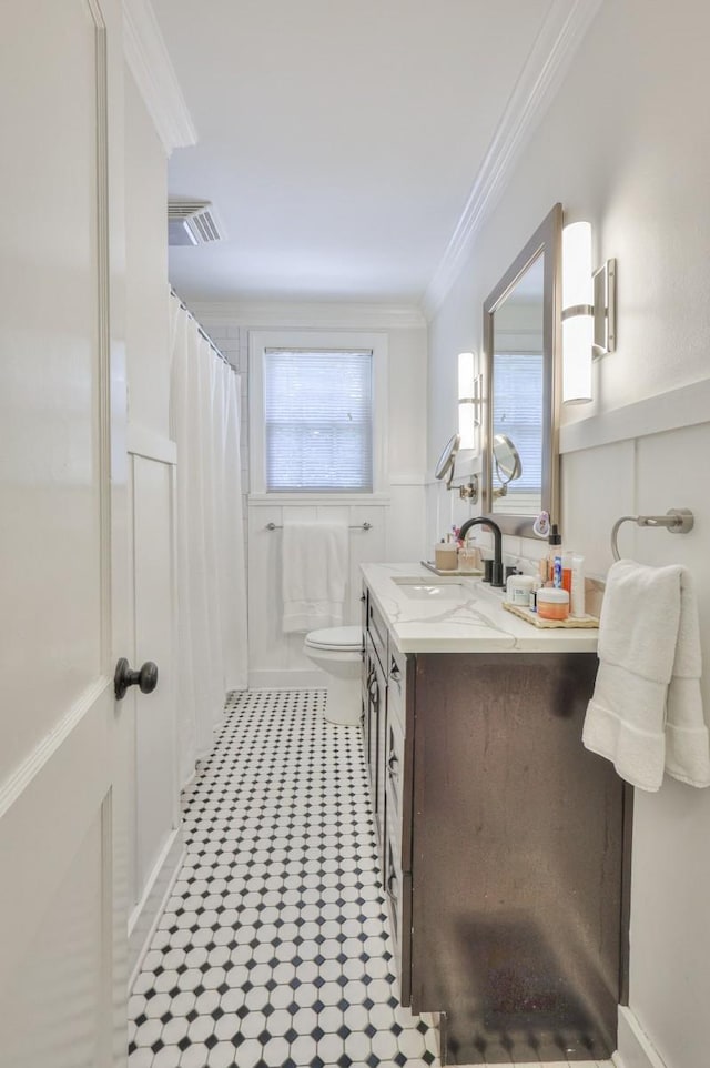 bathroom featuring a wealth of natural light, toilet, vanity, and crown molding