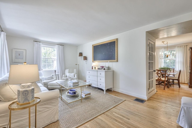 living room with light wood finished floors, visible vents, and baseboards