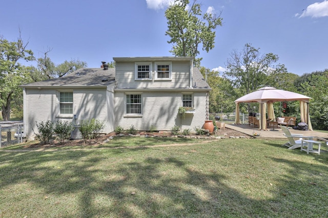 rear view of property featuring a gazebo, a yard, brick siding, and a patio