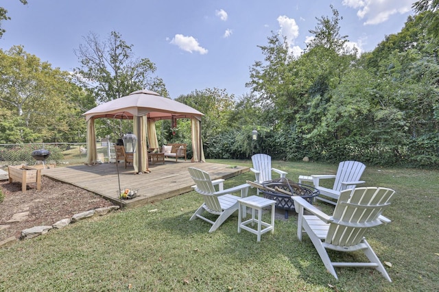 view of yard with a gazebo, a wooden deck, a fire pit, and fence