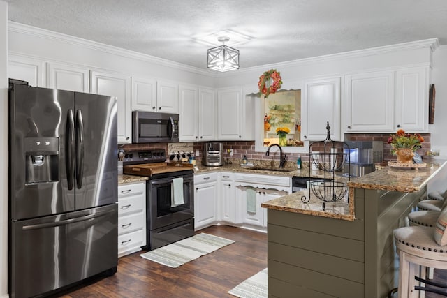 kitchen with black appliances, a sink, dark wood finished floors, white cabinetry, and a peninsula