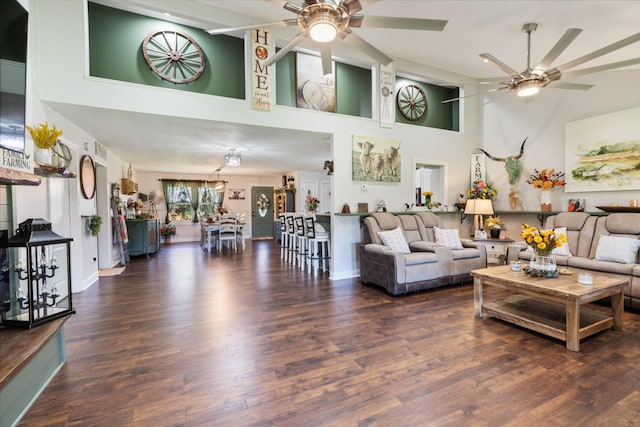 living area featuring a high ceiling, ceiling fan, and wood finished floors