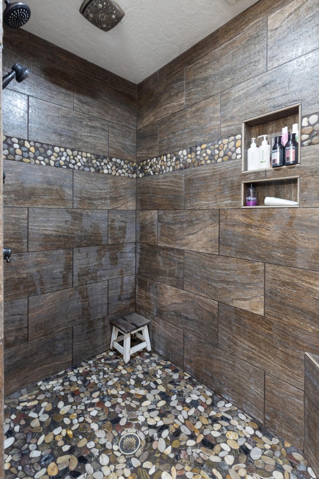 full bathroom featuring a tile shower and a textured ceiling