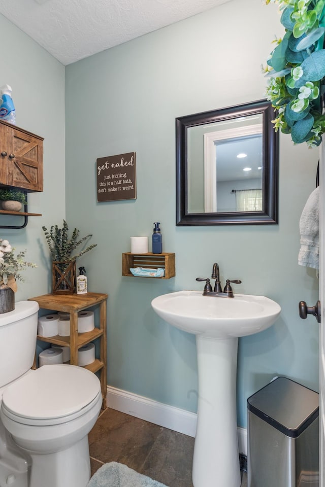 half bath featuring baseboards, toilet, wood finished floors, a textured ceiling, and a sink