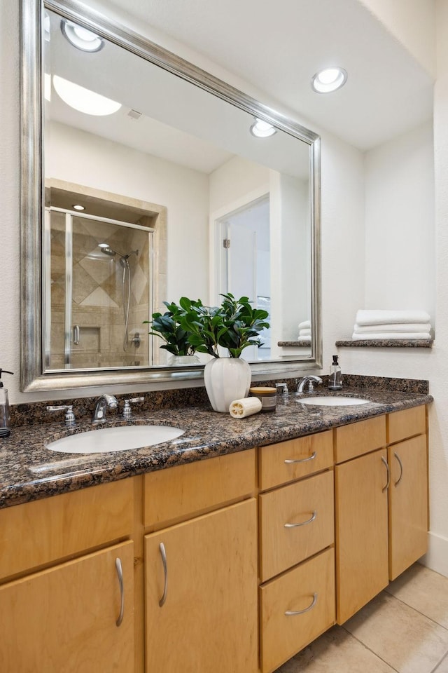 full bathroom featuring tile patterned flooring, double vanity, a stall shower, and a sink