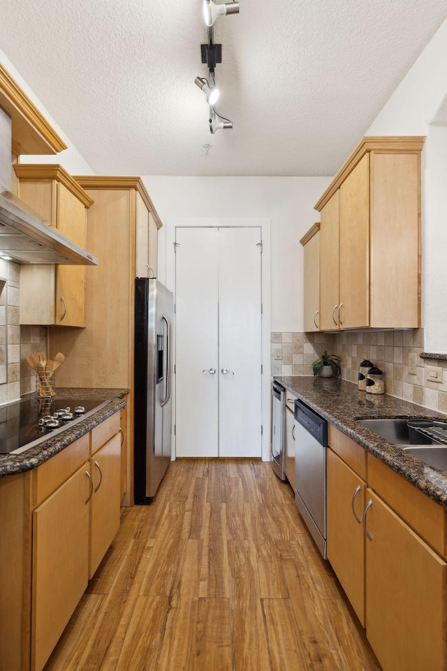 kitchen with light wood-style flooring, light brown cabinets, backsplash, a textured ceiling, and appliances with stainless steel finishes