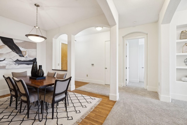 dining space featuring baseboards, arched walkways, and wood finished floors