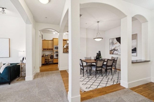 dining room featuring baseboards, arched walkways, and wood finished floors