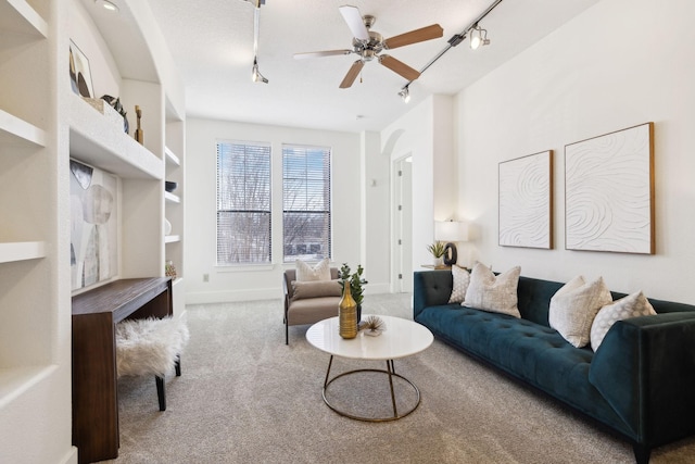 carpeted living area featuring track lighting, baseboards, and ceiling fan