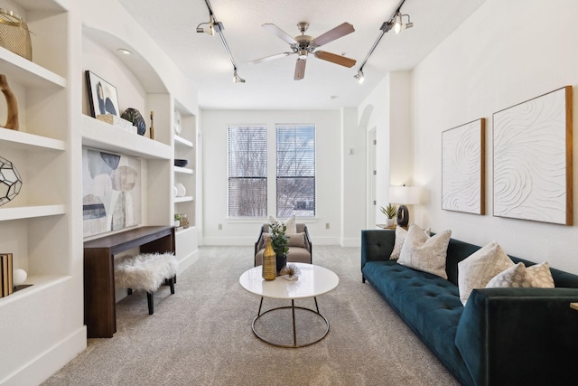 living room featuring built in features, a ceiling fan, baseboards, carpet floors, and track lighting