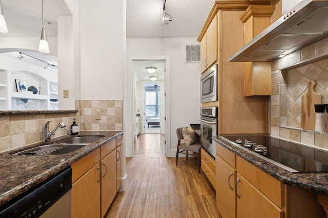 kitchen with range hood, visible vents, a sink, decorative backsplash, and stainless steel appliances