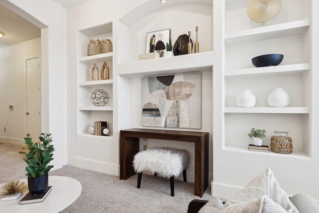 sitting room with built in features, baseboards, and carpet flooring