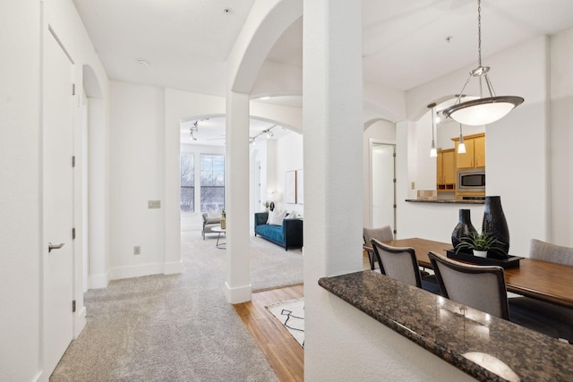 interior space with light brown cabinets, baseboards, light wood finished floors, arched walkways, and stainless steel microwave