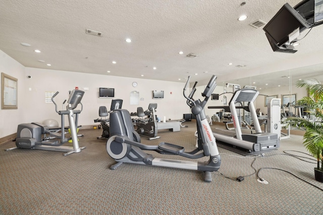 workout area featuring baseboards, visible vents, and a textured ceiling