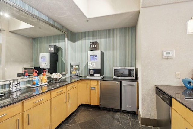 kitchen with dark stone counters, appliances with stainless steel finishes, and light brown cabinetry