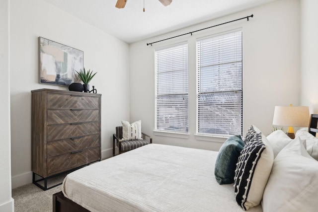 carpeted bedroom with ceiling fan and baseboards