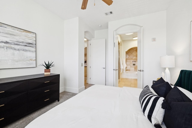 bedroom with visible vents, light carpet, ensuite bathroom, arched walkways, and ceiling fan