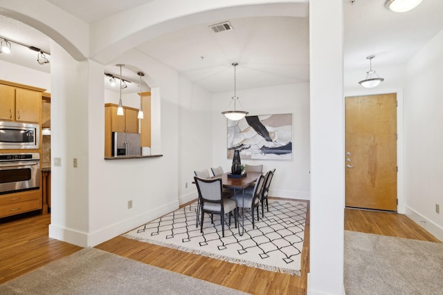 dining area with visible vents, arched walkways, baseboards, and wood finished floors