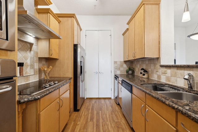 kitchen with light wood-style flooring, a sink, appliances with stainless steel finishes, wall chimney range hood, and stacked washer / drying machine