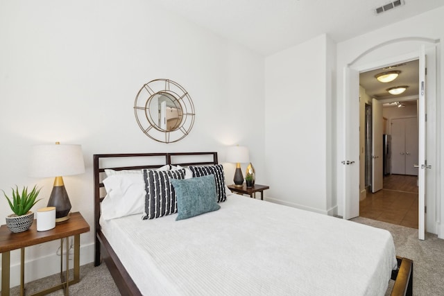 carpeted bedroom with visible vents, baseboards, and tile patterned flooring