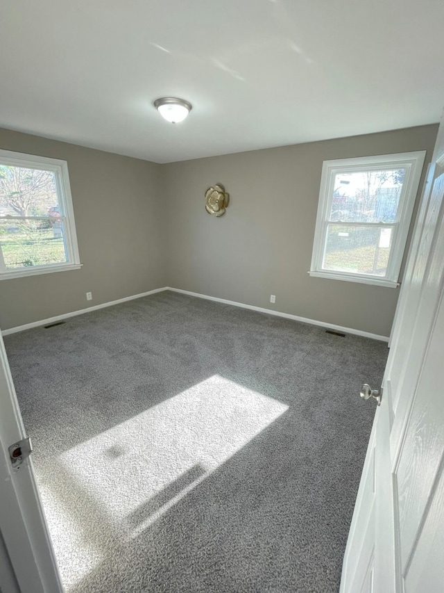 spare room featuring carpet flooring, visible vents, and baseboards