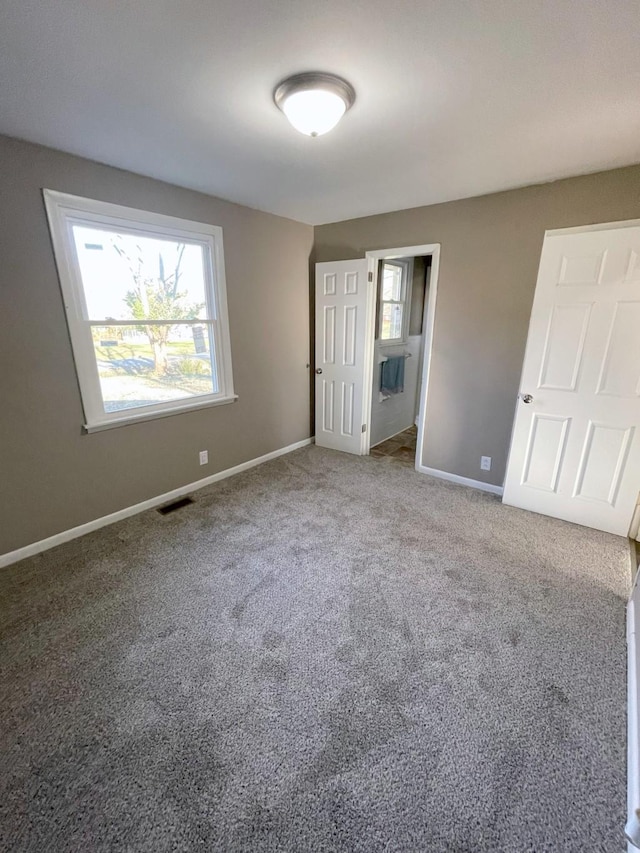 unfurnished bedroom with carpet flooring, baseboards, and visible vents