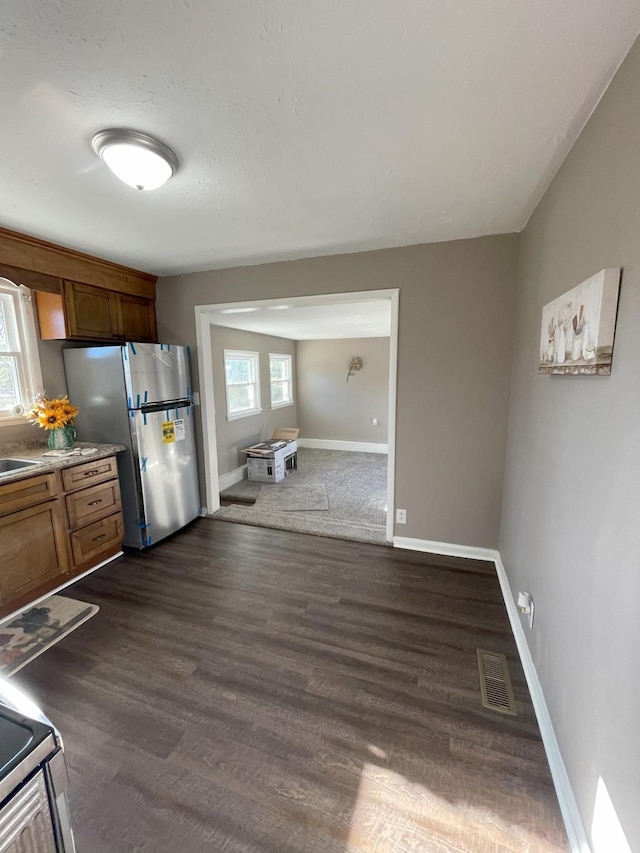 kitchen with brown cabinetry, baseboards, visible vents, stainless steel appliances, and dark wood-type flooring