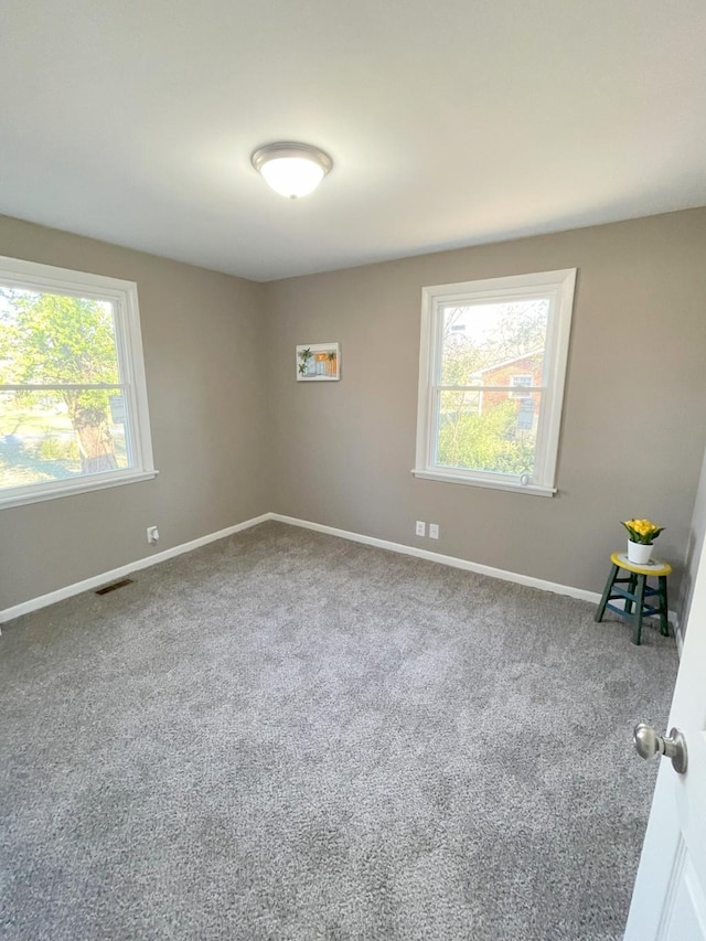 carpeted spare room with baseboards and visible vents