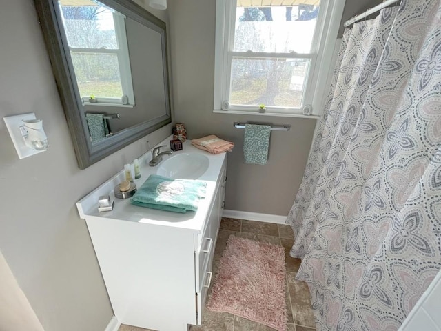 full bath featuring vanity, tile patterned floors, baseboards, and a wealth of natural light