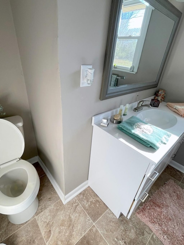 half bathroom featuring vanity, toilet, and baseboards