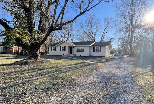 single story home featuring gravel driveway, a front yard, and stucco siding