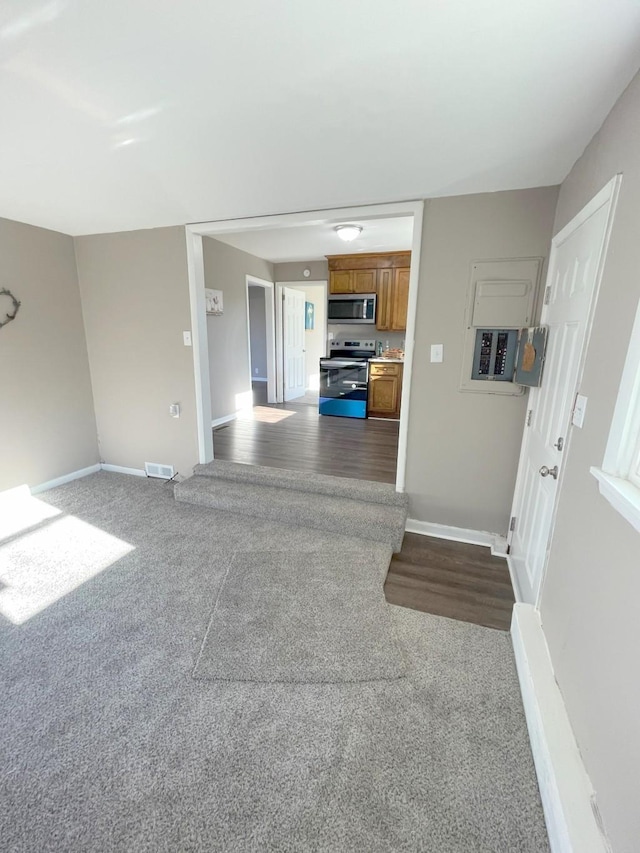 unfurnished living room featuring visible vents, baseboards, and dark colored carpet