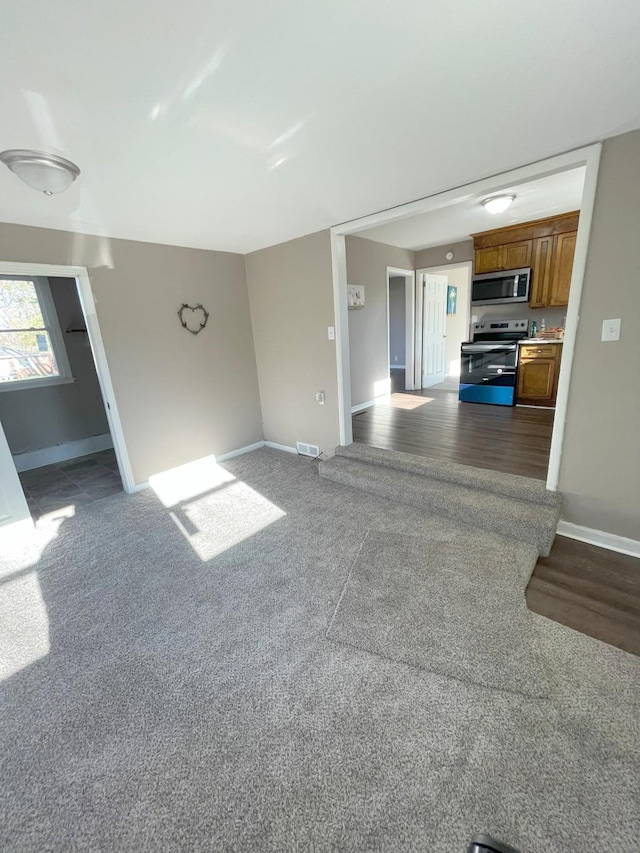 unfurnished living room featuring visible vents, baseboards, and dark colored carpet