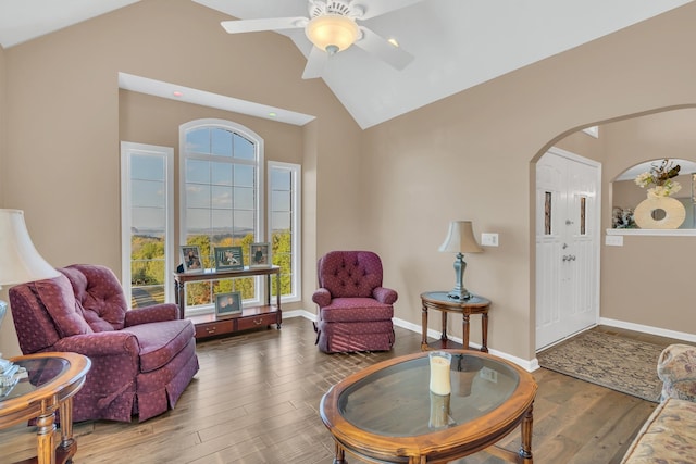 sitting room with a ceiling fan, wood finished floors, baseboards, arched walkways, and vaulted ceiling