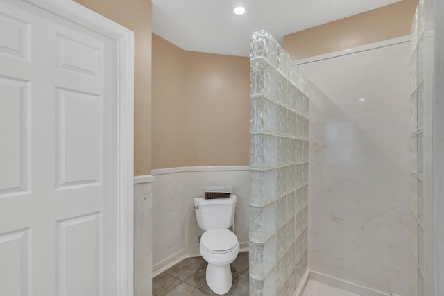 full bathroom featuring a wainscoted wall, toilet, walk in shower, and tile patterned flooring