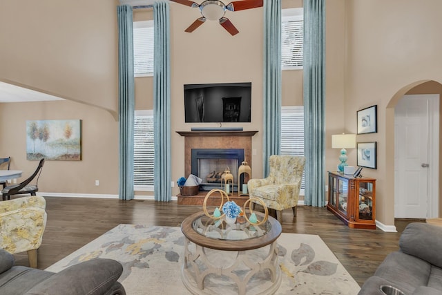 living room featuring arched walkways, ceiling fan, a high ceiling, and a wealth of natural light