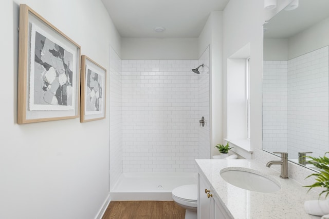 bathroom with toilet, a shower stall, wood finished floors, and vanity