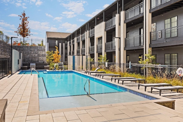 pool with a patio area and fence