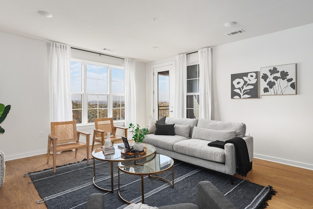 living area featuring visible vents, wood finished floors, and baseboards