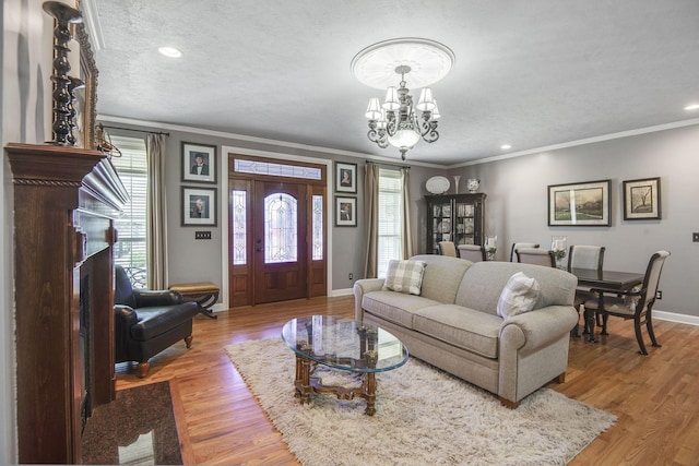 living area featuring baseboards, ornamental molding, recessed lighting, wood finished floors, and a notable chandelier