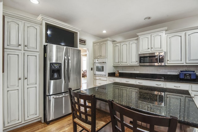 kitchen featuring dark stone counters, recessed lighting, light wood-style floors, appliances with stainless steel finishes, and tasteful backsplash