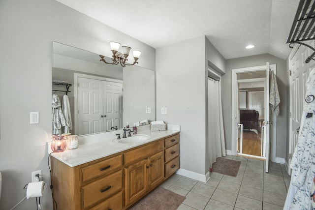 bathroom featuring vanity, baseboards, an inviting chandelier, tile patterned flooring, and a closet