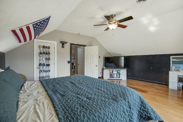 bedroom with ceiling fan, wood finished floors, and vaulted ceiling