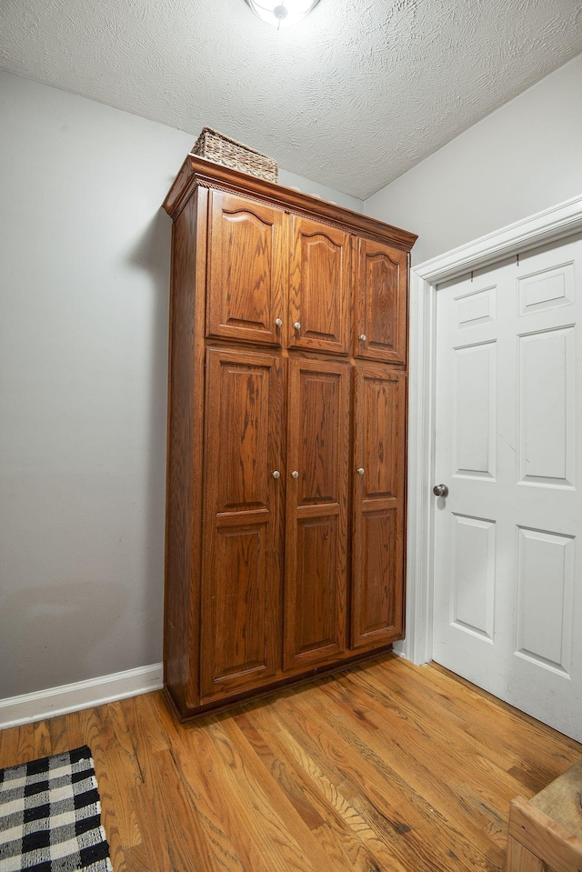 details with baseboards, a textured ceiling, and wood finished floors