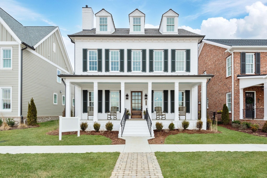 view of front of home with a chimney, a porch, and a front lawn