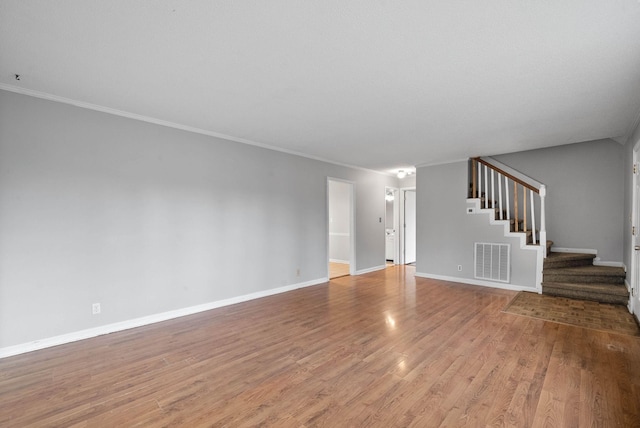 unfurnished living room with visible vents, wood finished floors, stairway, crown molding, and baseboards