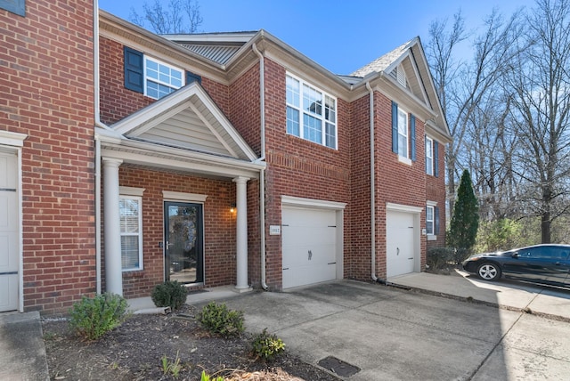 view of property featuring a garage, brick siding, and driveway