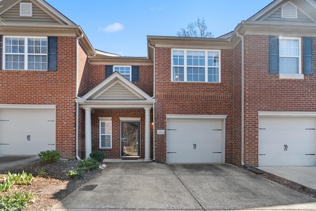 townhome / multi-family property with brick siding, driveway, and a garage