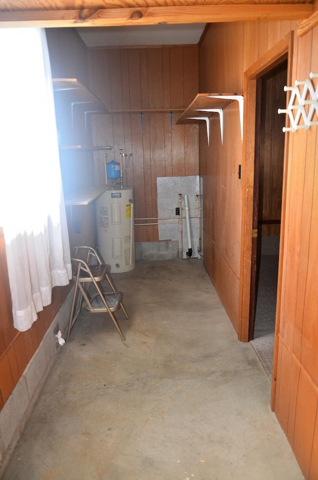 basement featuring water heater and wood walls